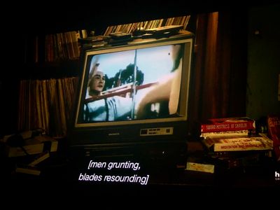 an old tv on a messy shelf with VHS tapes, playing a kung fu movie
