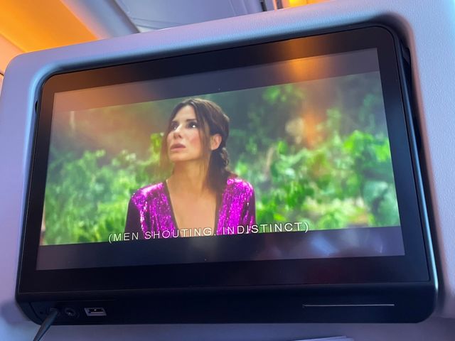 Sandra Bullock in pink sequins seems distraught surrounded by vegetation
