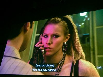 Teenage girl talking on a flip phone, with star earrings and a fingerless lace wrist-warmer - we see a man's shoulder facing her
