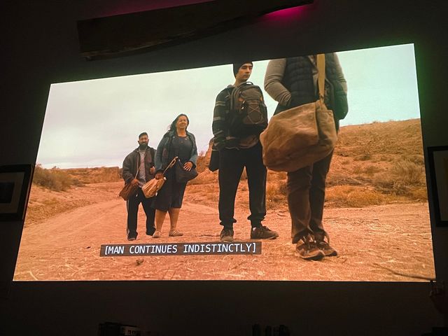 Four people carrying bags along a desert road
