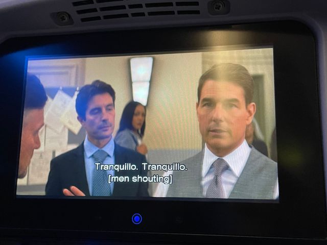 Tom Cruise in a tie and vest talking to men in suits
