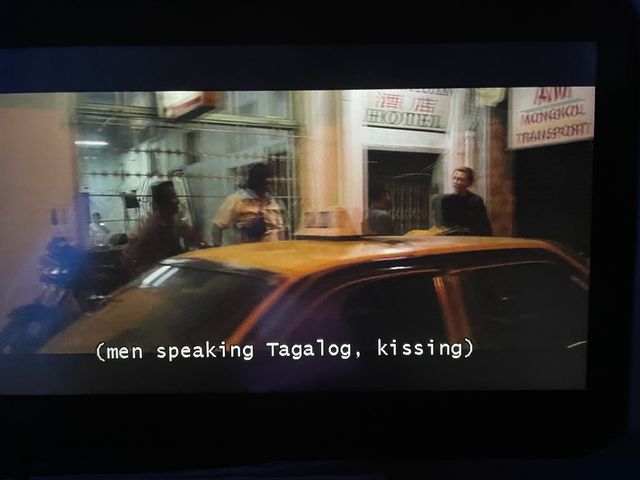 blurry image, a taxi and three men in front of a building with signs that contain both english words and asian characters
